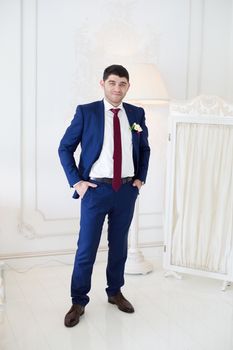 gorgeous brunette bride putting on boutonniere on the blue suit of groom