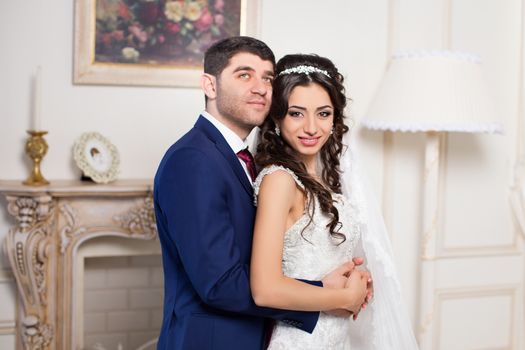 Stylish newlyweds posing for the camera in the apartment