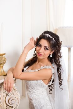 beautiful brunette bride in a luxurious wedding dress posing in interior