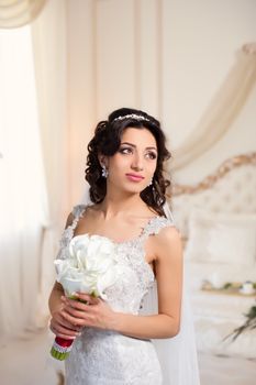 beautiful brunette bride in a luxurious wedding dress posing in interior