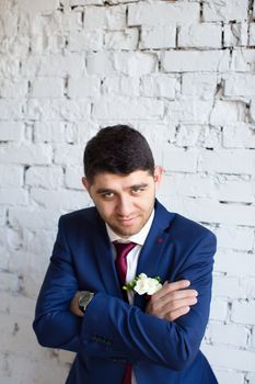 gorgeous brunette bride putting on boutonniere on the blue suit of groom
