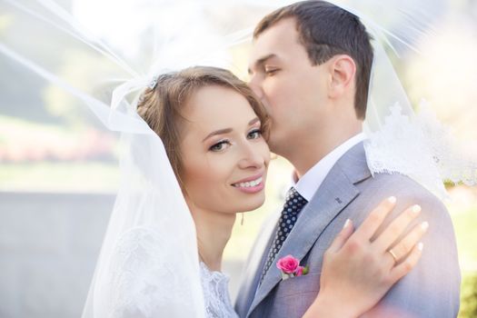 Bride and groom at wedding Day walking Outdoors on spring nature. Bridal couple, Happy Newlywed woman and man embracing in green park. Loving wedding couple outdoor. Bride and groom