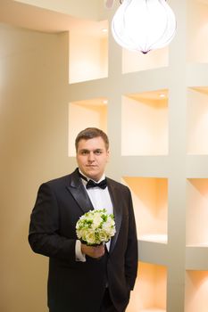 A close-up shot of a man straightening his tux.