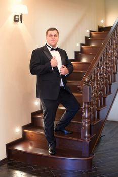 A close-up shot of a man straightening his tux.