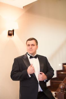 A close-up shot of a man straightening his tux.