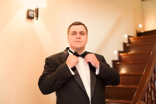 A close-up shot of a man straightening his tux.