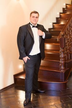 A close-up shot of a man straightening his tux.