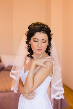 Stylish brunette bride near old vintage pink house with columns