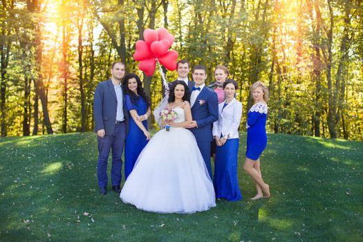 Newlyweds having fun with the guests in a meadow in the park