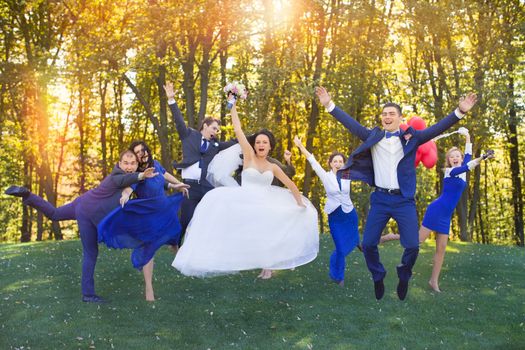 Newlyweds having fun with the guests in a meadow in the park