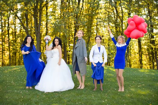 Outdoor portrait of beautiful young bride with her female friends