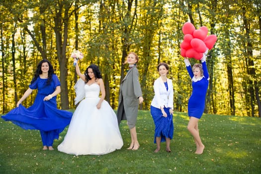 Outdoor portrait of beautiful young bride with her female friends