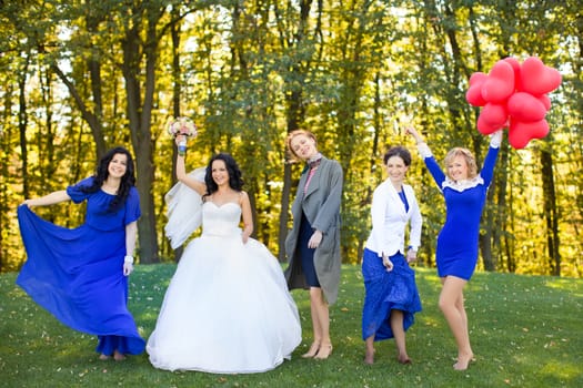 Outdoor portrait of beautiful young bride with her female friends