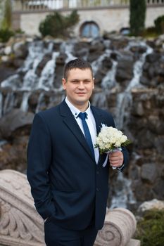 Portrait of the groom's great in a dark suit on the street