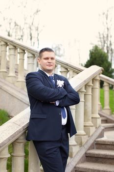 Portrait of the groom's great in a dark suit on the street