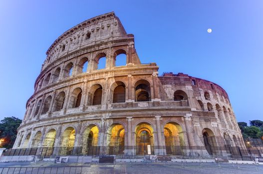 Coliseum by night with full moon in Roma, Italy