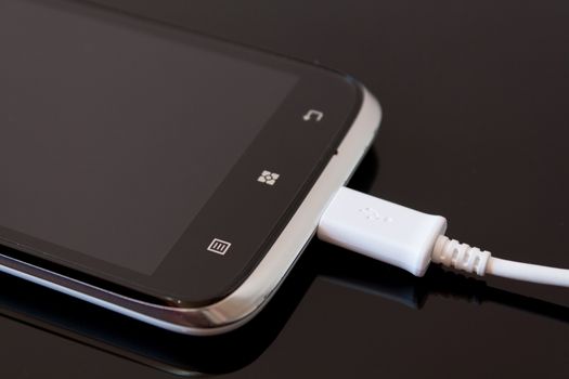 Black Smart Phone Charging with Cable on the Black Table