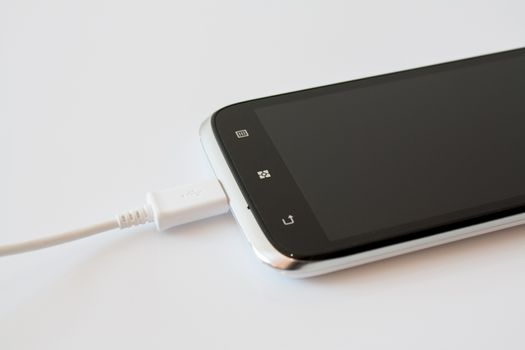 Black Smart Phone Charging with Cable on the white Table