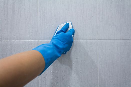 man in gloves cleans a tile on bathroom