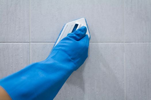 man in gloves cleans a tile on bathroom