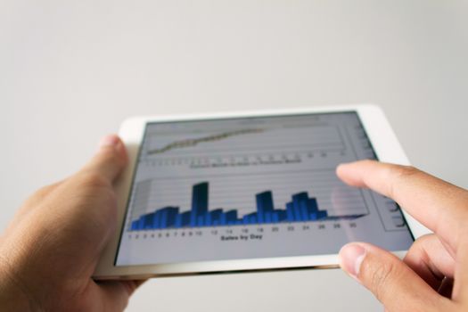 Businessman hand touching screen of tablet computer with market graph