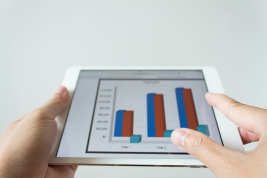 Businessman hand touching screen of tablet computer with market graph