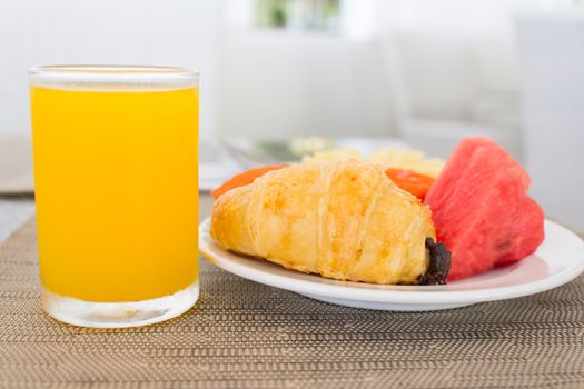 Breakfast with orange juice, croissant and fruits on dinning table