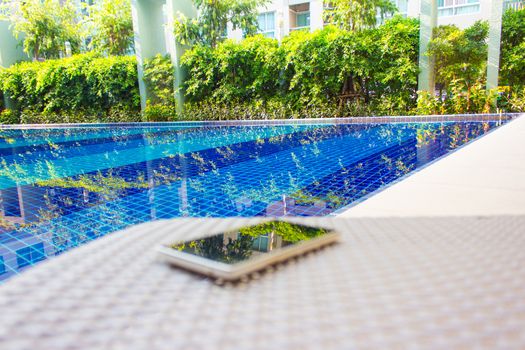 Smartphone put on armchair beside the pool means to get resting  away from business