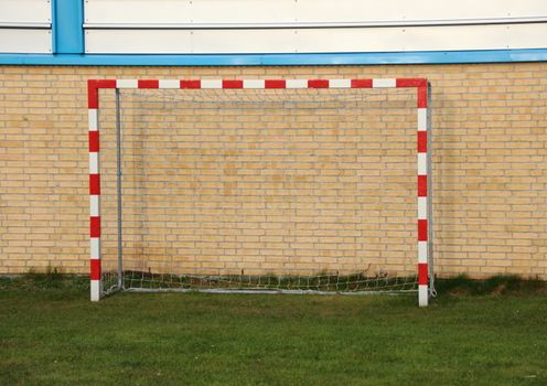 Empty outdoor handball goal with wall in background