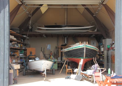 Inside small ship workshop with two boats under repair