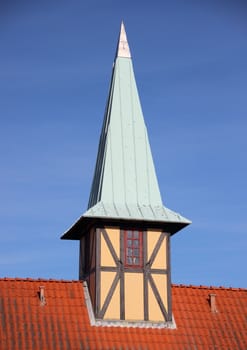Half-timbering tower with verdigris roof on red tile building