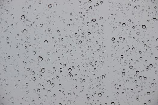 Raindrops on window with black stormy weather outside