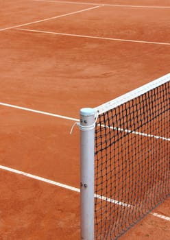 Tennis net at empty red gravel court