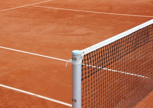 Tennis net at empty red gravel court