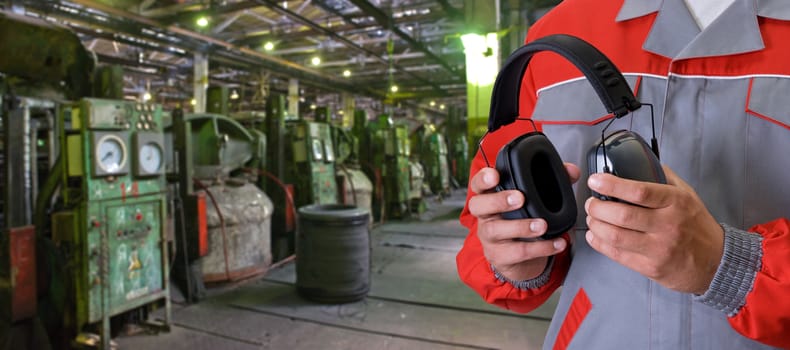 Worker with protective headphone at man hands at industrial factory