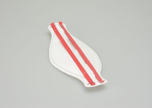 The N95 mask, oval shape, ear hook have red belt placed on white background.