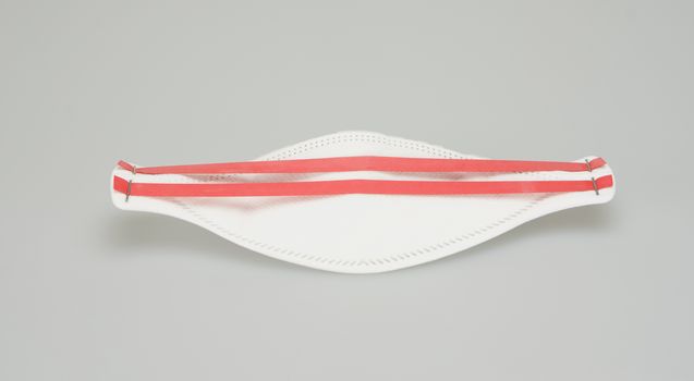 The N95 mask, oval shape, ear hook have red belt placed on white background.