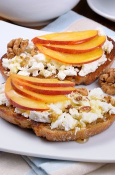 Sandwich of oat bread with ricotta and slices of peach, nuts, watering honey