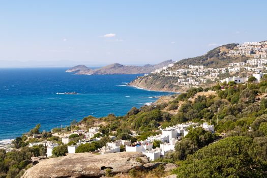 Seascape view of coastline with blue bright sea with small hills.