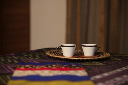 Bedside tea served in two cups in a tray, on a bed in a bedroom.