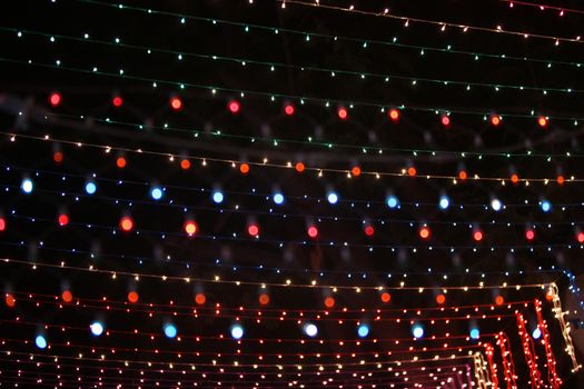 A background of colorful light wires setup high for decoration during a festival.