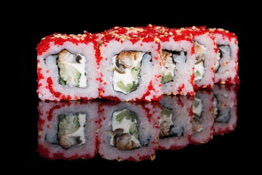 Sushi rolls with soft cheese, eel, cucumber and flying fish roe on black background
