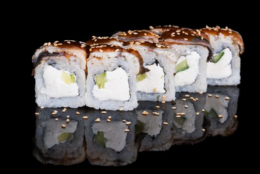 Sushi rolls with eel, cucumber and soft cheese on black background