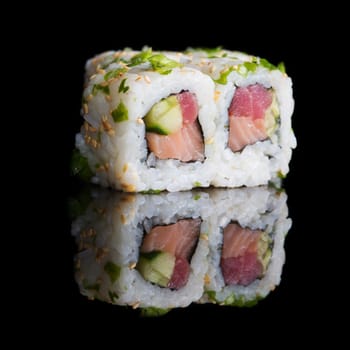 Sushi rolls with salmon, tuna, cucumber and green onions on black background