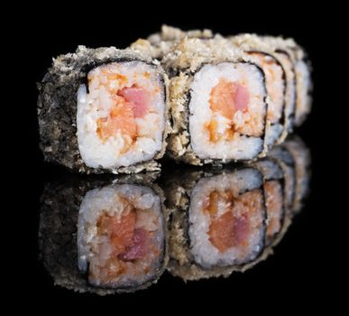 Grilled sushi rolls with salmon, tuna and eel on black background