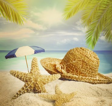 Sandy beach, straw hat and starfish in summer