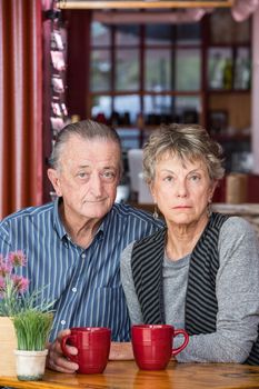 Serious mature couple sitting next to each other in a coffee house