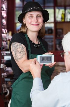 Smiling waitress in green apron holding smart phone with coupon code for customer
