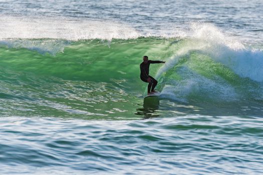 Long boarder surfing the waves at sunset in Portugal.