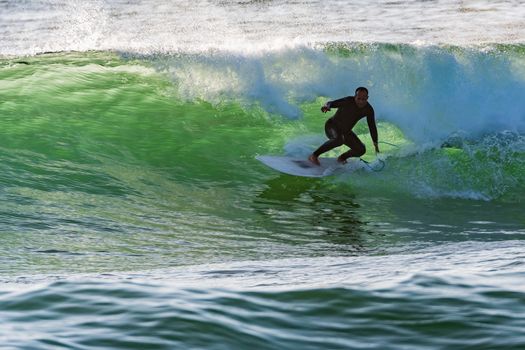 Long boarder surfing the waves at sunset in Portugal.